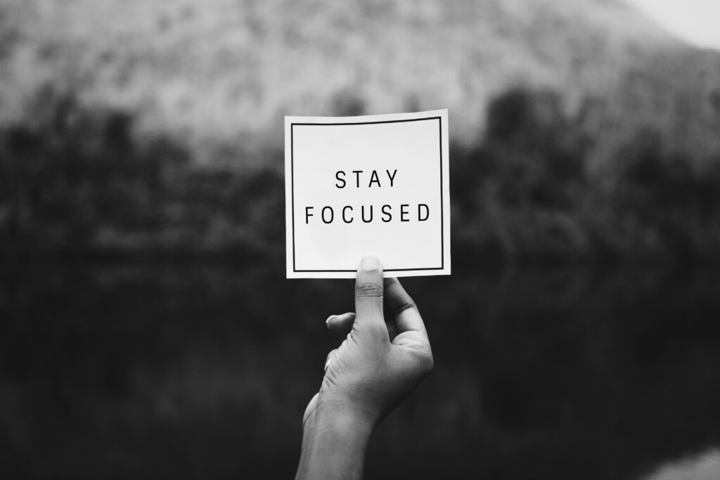 Hand holding 'Stay Focused' sign.